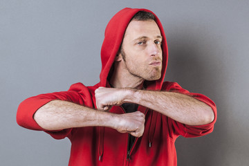 male power concept - pouting 40s man wearing an adolescent hooded sweater showing his strength with both fists and arms wide open,studio shot