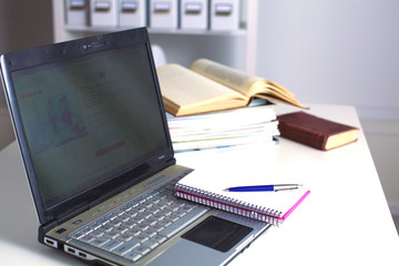 Office table with blank notepad and laptop 