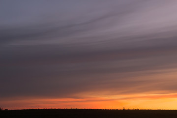 Moody clouds sweeping across a peach sunset in the country