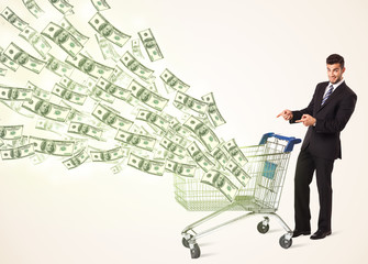 Businessman with shopping cart with dollar bills