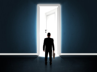 Obraz premium Business man looking at big bright opened door