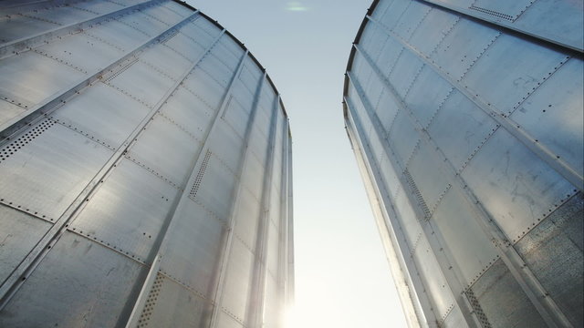 Silver, shiny agricultural silos. Two of the tower and between sun