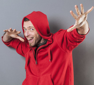male adolescence concept - ecstatic middle age wearing a red hooded sweater playing rapper with fun hand gesture,studio
