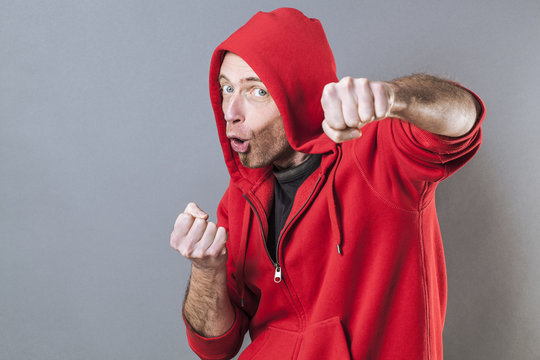 male adolescence concept - fighting middle age wearing a red hooded sweater playing rapper with fun hand gesture,studio