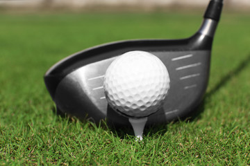 Golf club and ball on a green grass, close up