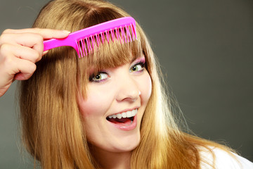 Closeup woman combing her fringe with pink comb