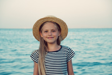 Счастливая девочка на море в соломенной шляпке.  