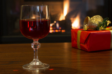 Glass of Red Wine With Christmas Decorations and Fireplace in Background
