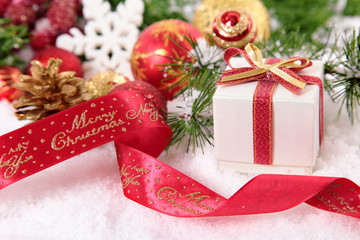Christmas decorations, ribbon and gift on the snow