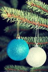 Two christmas balls hanging on a tree.