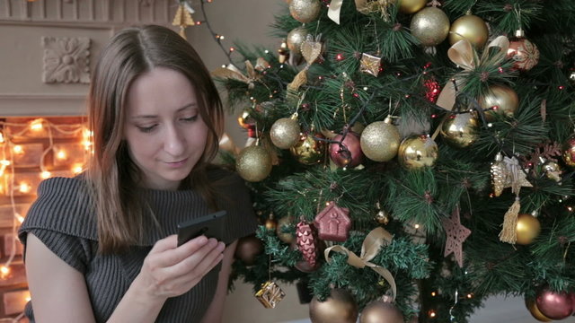 Woman using her mobile phone at christmas at home in the living room