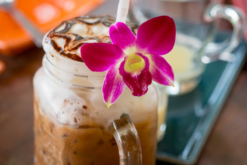 Iced coffee with milk in vintage jar and orchid flower decoratio