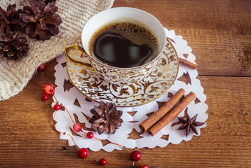 Photo of glowing white and golden cup with tasty coffee, Christmastime table setting, tea mug on brown wooden background, snowflake decoration, New Year ornament, Christmas home decor with warm scarf 