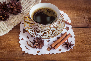 Photo of glowing white and golden cup with tasty coffee, Christmastime table setting, tea mug on brown wooden background, snowflake decoration, New Year ornament, Christmas home decor with warm scarf 