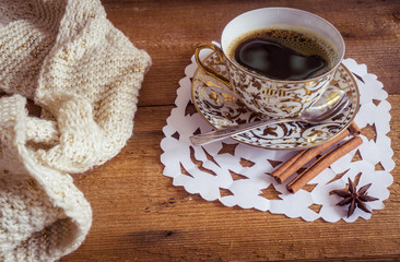 Photo of glowing white and golden cup with tasty coffee, Christmastime table setting, tea mug on brown wooden background, snowflake decoration, New Year ornament, Christmas home decor with warm scarf 