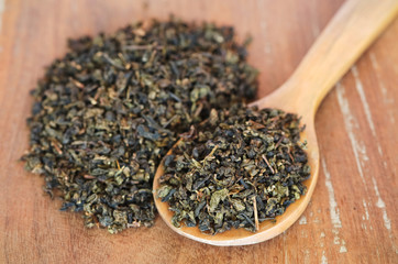 Dry organic tea in wooden spoon on wooden background