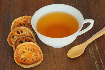 cup of bael juice with wooden spoon on wooden background