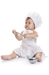 Funny adorable baby boy chef sitting and playing with kitchen equipment