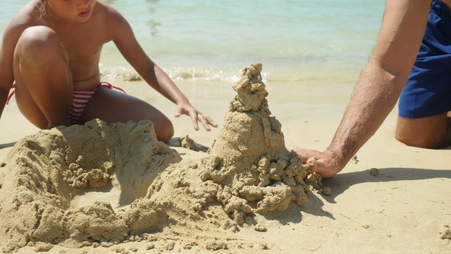 Family playing on the beach building sand castle. 4K UHD