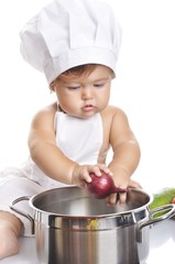 Funny adorable baby boy chef sitting and playing with kitchen equipment