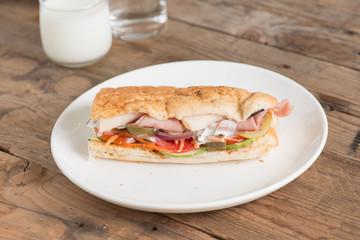 Long sandwich with chicken ham and pork ham on white plate.