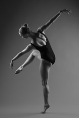 Fototapeta na wymiar Modern ballet dancer posing on dark background