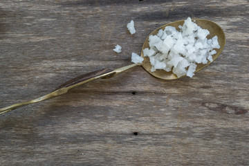 Sea salt in a brass spoon on wooden background