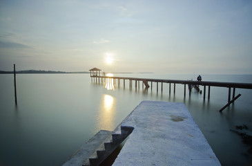Fototapeta na wymiar a man sitting on the bridge alone during sunset