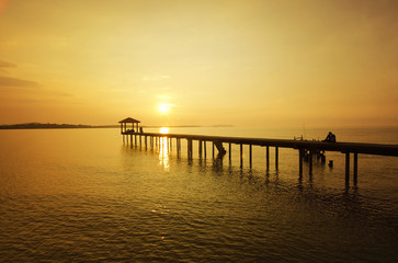 Fototapeta na wymiar silhouette of a man sitting on the bridge alone during sunset