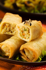 Portion baked spring rolls with vegetables and rice on a plate.
