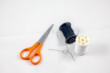 Black and white color thread with orange scissors 