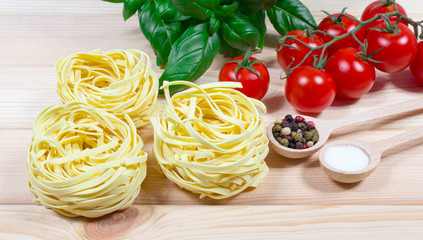 Raw homemade pasta and ingredients for pasta with tomatoes and basil.