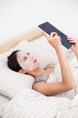 Woman using the tablet pc and facial mask