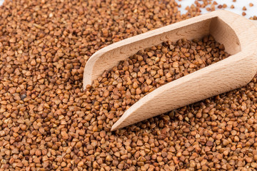 Uncooked buckwheat on wooden spoon