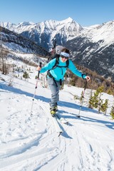 Fototapeta na wymiar Young woman ascending a slope on skis.