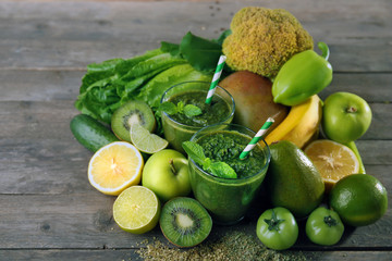 Green healthy juice with fruits and vegetables on wooden table close up