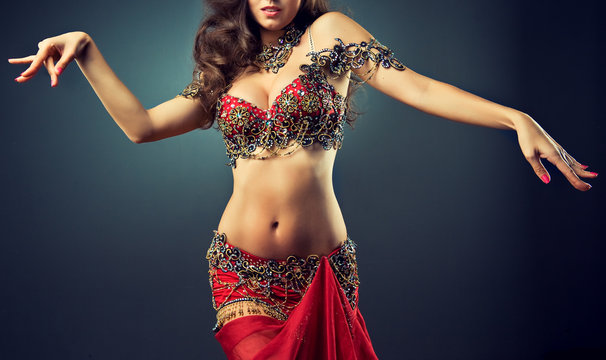 
Graceful girl dancing belly dance . Belly dance in plastic movement of the dance. Red dress for belly dance with sequins and rhinestones and jewelry