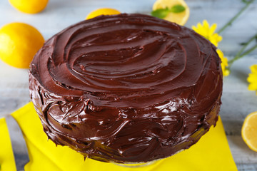 delicious chocolate cake near lemons on grey wooden table