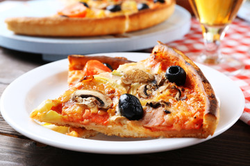 Sliced pizza served with beer on wooden table