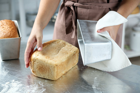 Baker with freshly baked bread in kitchen of bakery