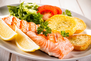 Fried salmon and vegetables on white background