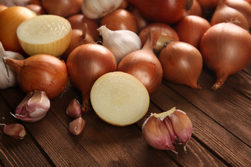 Fresh onions with garlic on wooden background