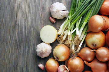 Fresh different onions with garlic on wooden background