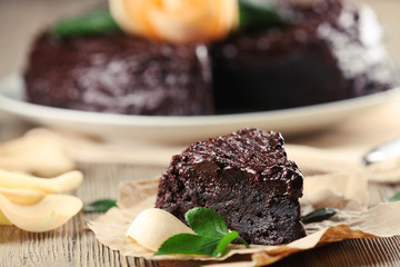 Piece of chocolate cake decorated with flowers on brown wooden table