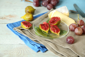 Ripe figs on plate, on color wooden background