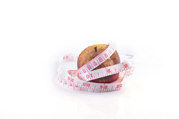 Wilted rotten apple and measuring tape on white background. Diet
