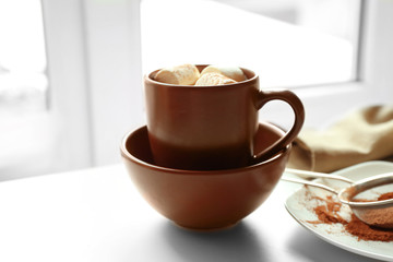 Cup of coffee with marsh mellow on a table in kitchen