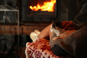 Woman resting with cat near fireplace