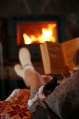 Woman resting with book near fireplace