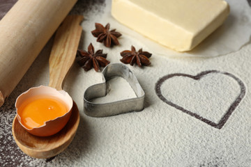 Fototapeta na wymiar Heart of flour and kitchen utensils on wooden background